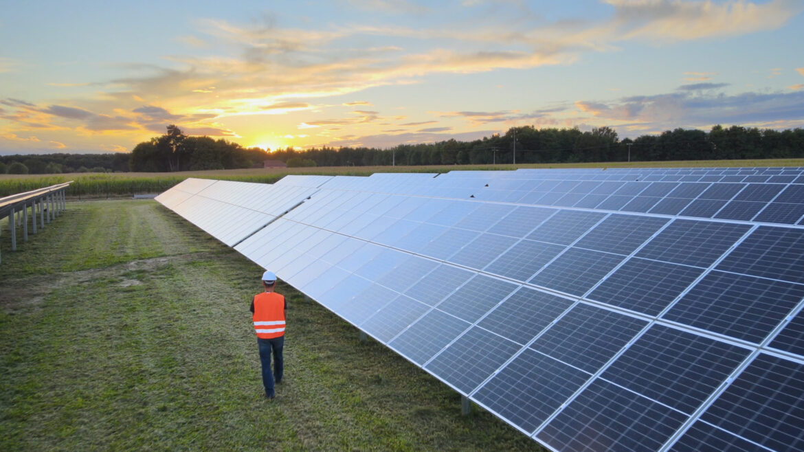 Aerial drone view following a Technician at work on a solar farm